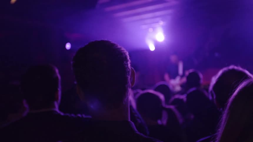 A crowd is watching people perform in a dark area