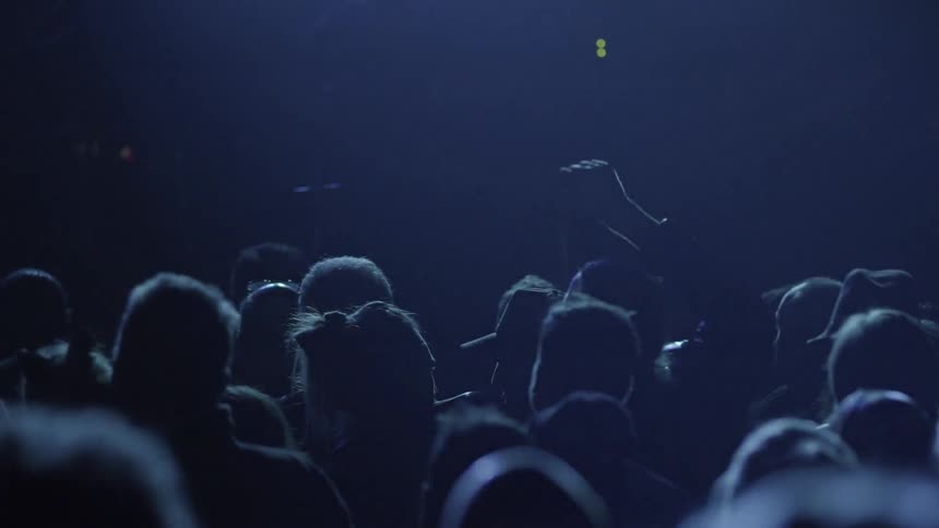 Lights flash and people jump and dance at a concert