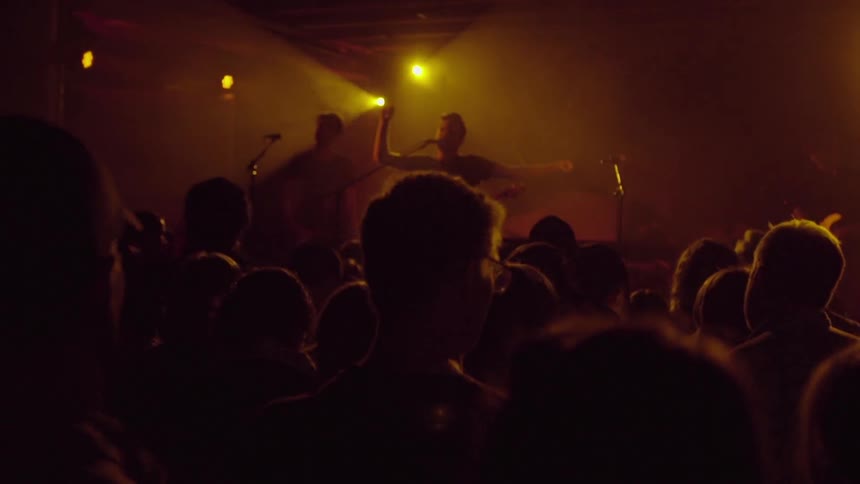 A crowd sways and bops as they watch a band on stage