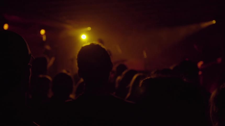 A crowd is watching a band play in a dark area
