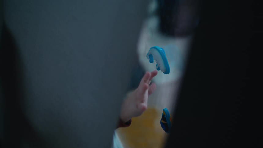 Blonde toddler boy plays with toys on window