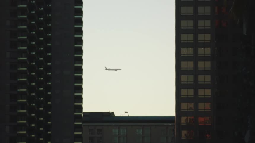 A passenger plane flies past tall skyscrapers