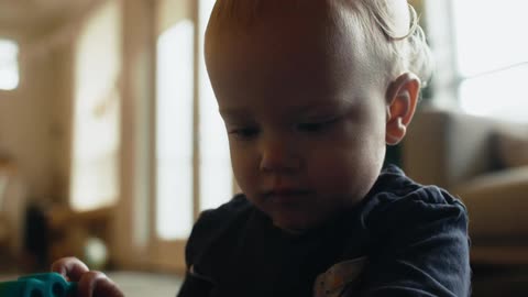A young child sitting on the family room floor concentrating on his toys