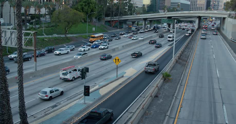 Traffic moves through underpasses as it goes in and out of a big city and tall buildings and skyscrapers are in the distance