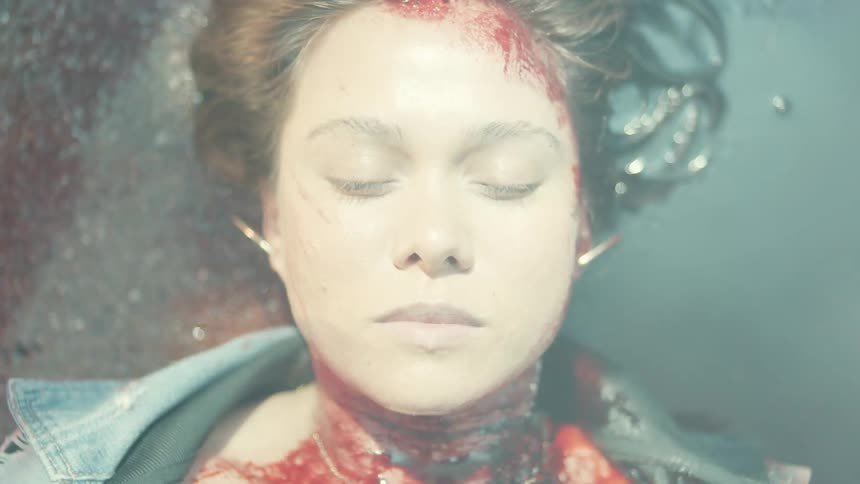 An injured woman is bleeding out on the ground as medics tend to her