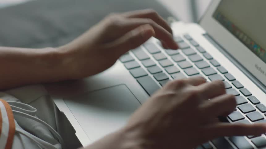 A persons hands are typing on a computer keyboard