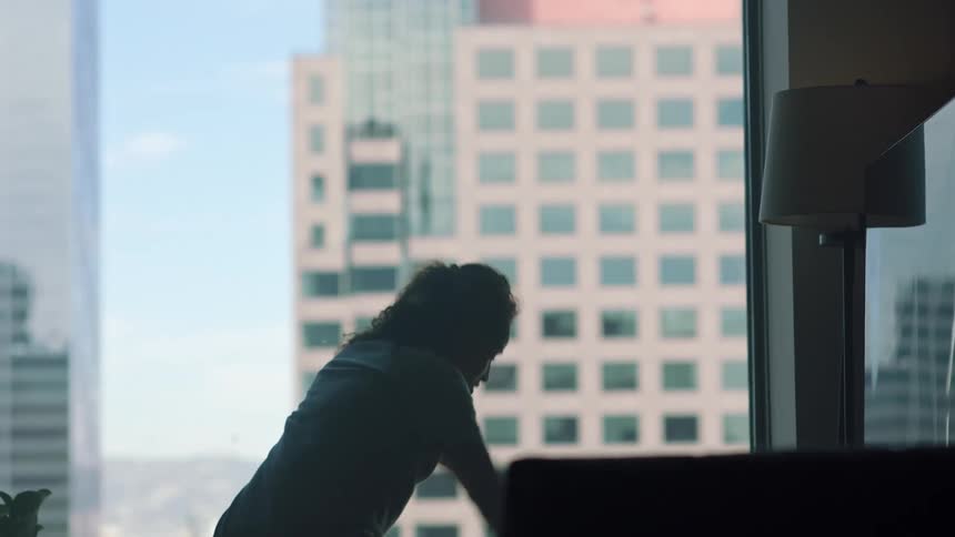 A woman skips twirls and dances through her apartment in front of large windows