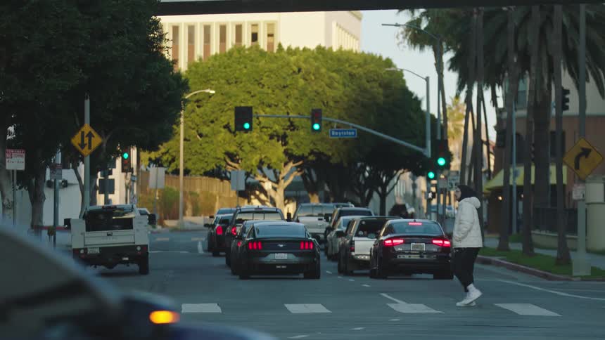 Vehicles are driving through a downtown city at midday