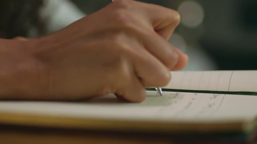 Woman writes in journal with a pen