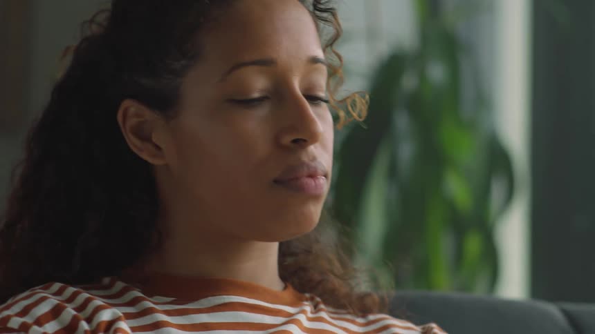 A woman bobs her head while sitting on the couch