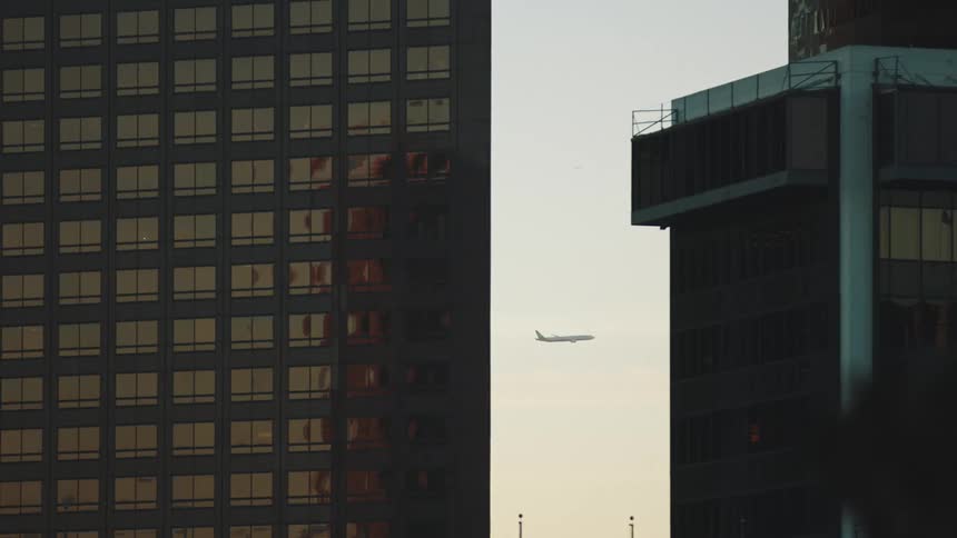 An airplane flies past tall apartment buildings