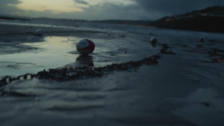 The football rolls on the beach