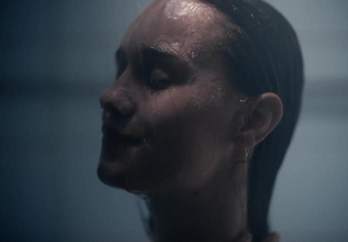 A woman reaches to smooth her hair as she showers