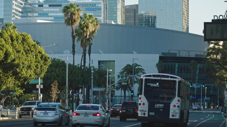 Vehicles driving down a city street with office buildings in the background