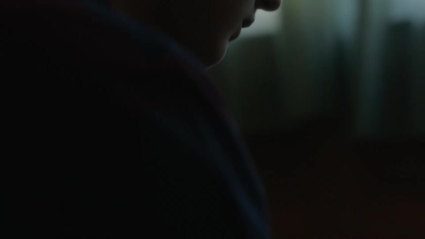 A child is sitting in his room and holding a football