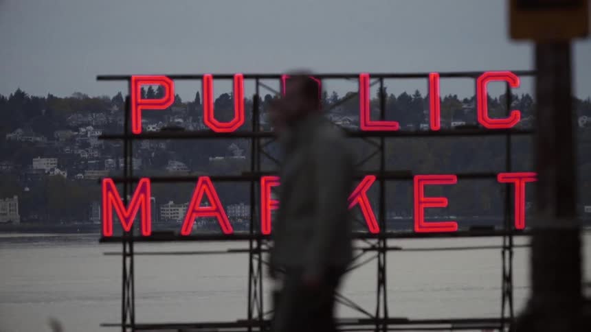 People walk in front of a red neon sign