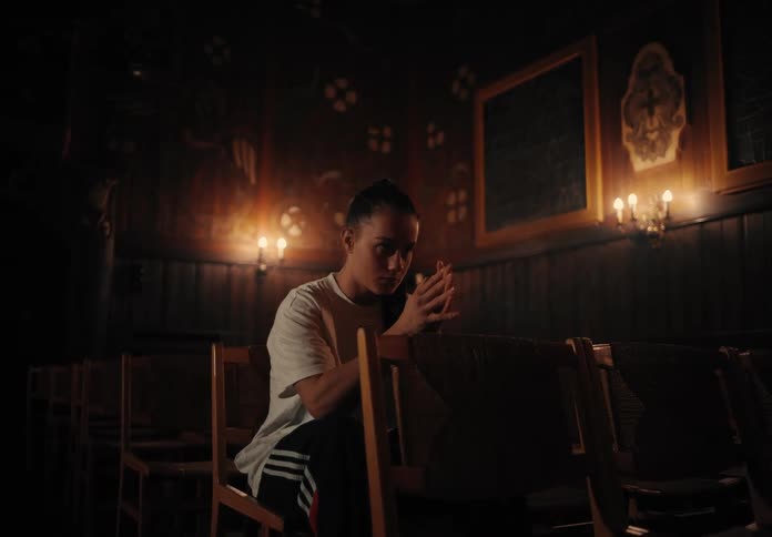 A woman sits and prays in the back of a church
