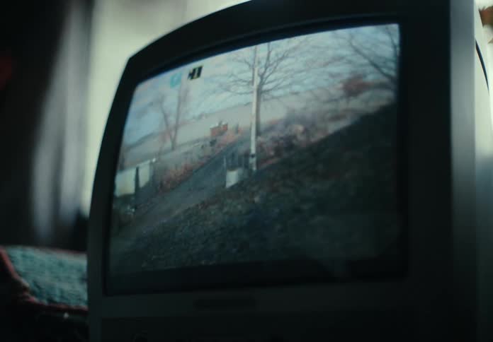 Static lines move across a TV screen showing security footage of a woman running