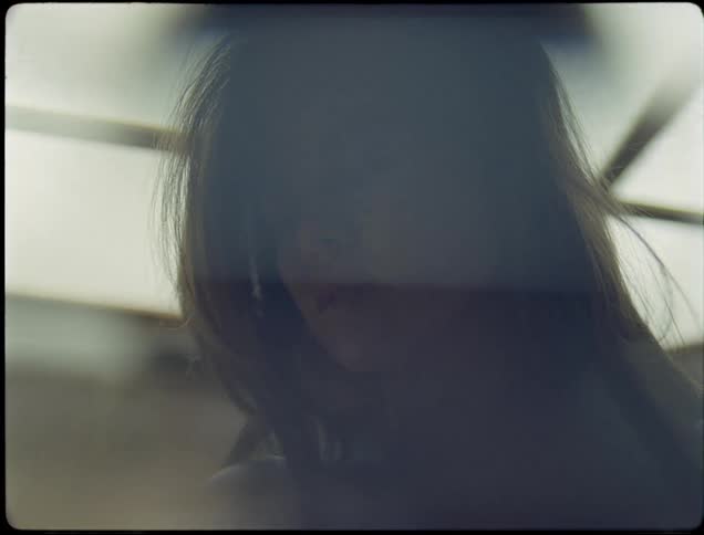 A teenage girl brushes her hair out of her face and then the camera moves down to a large scar on her chest