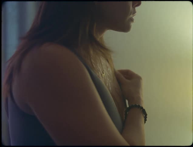 Woman examines scars on her chest before walking away