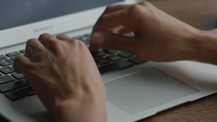 A person is typing on a laptop while sitting indoors