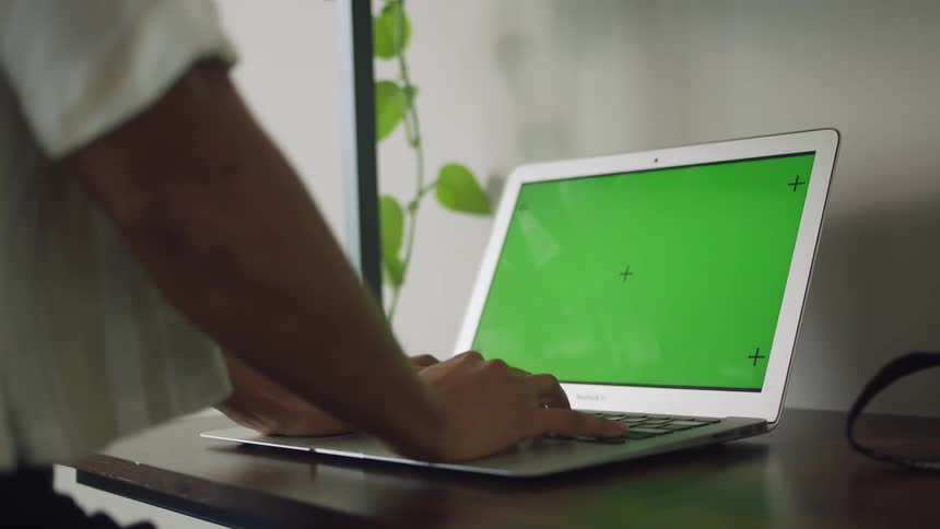 A person is typing on a laptop in a room