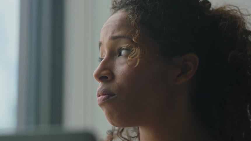 Woman using laptop feels upset and looks away in room