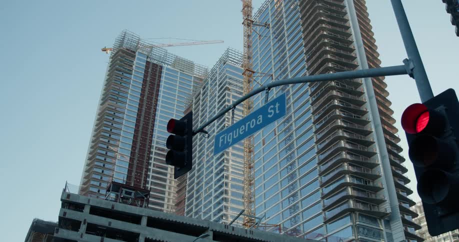 Figueroa street sign hanging from a traffic light near skyscrapers that are under construction