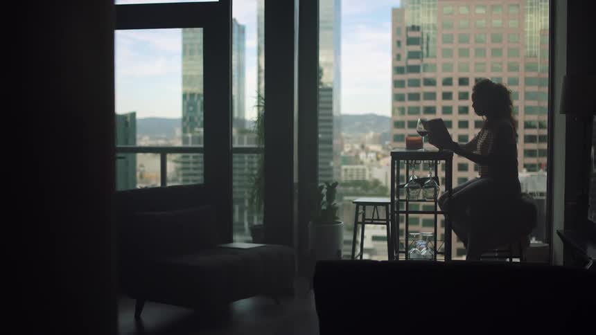A woman reads a book at her kitchen table with views of downtown