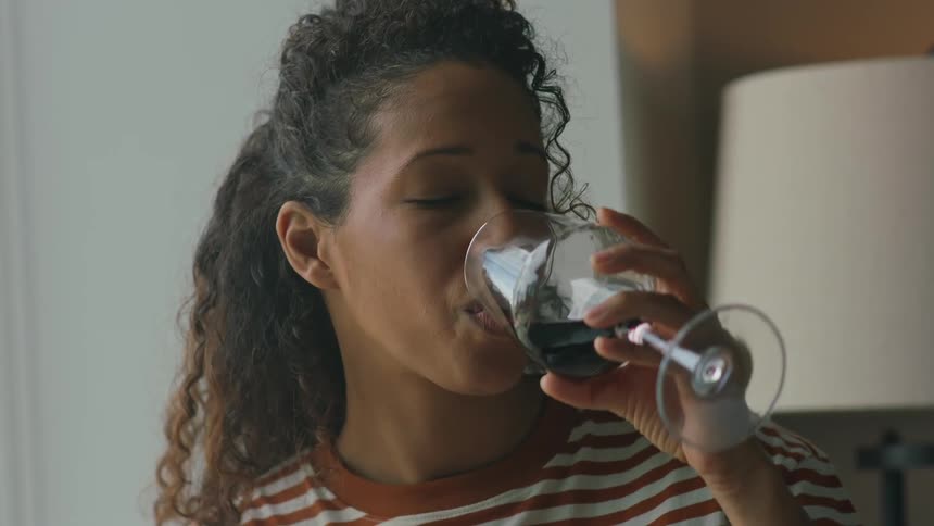 A woman is reading a book and drinking a glass of wine