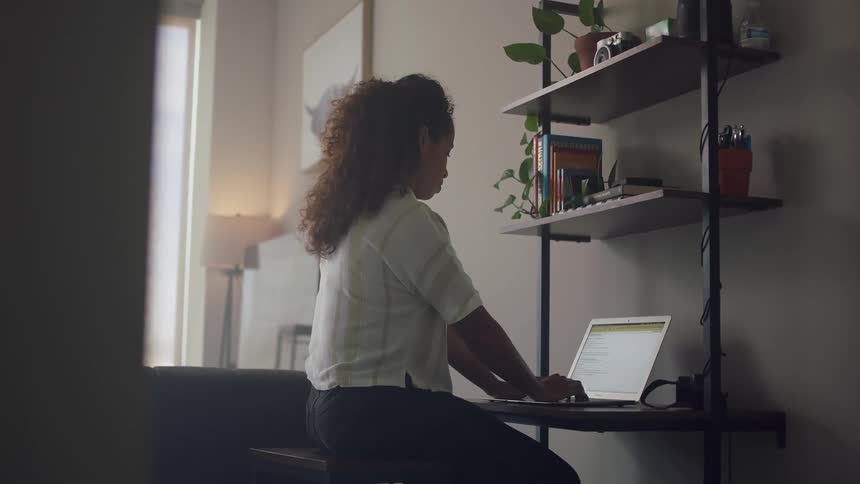 A woman sits at home and uses a laptop