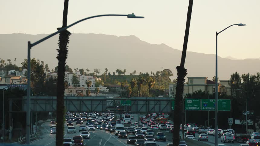Cars are driving on a highway near a downtown city