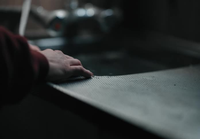 A hand resting on the counter while waiting for a sink to fill with water