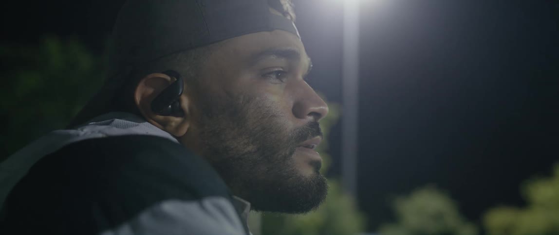 A younger black man is outside in the dark at night time