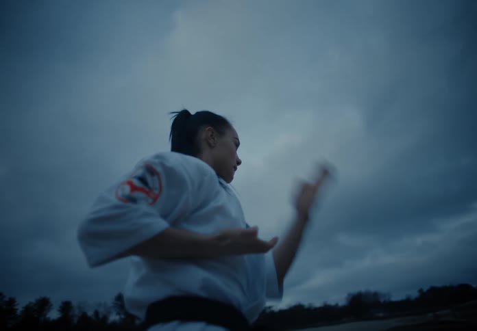 A woman is practicing martial arts outdoors