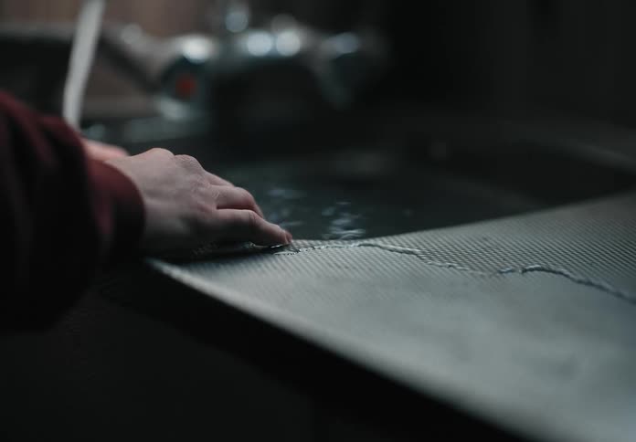Person stands at kitchen sink as it fills and overflows with water