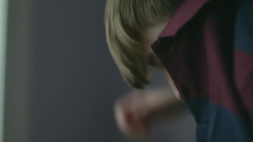 A teenage boy pulls a shirt on over his head