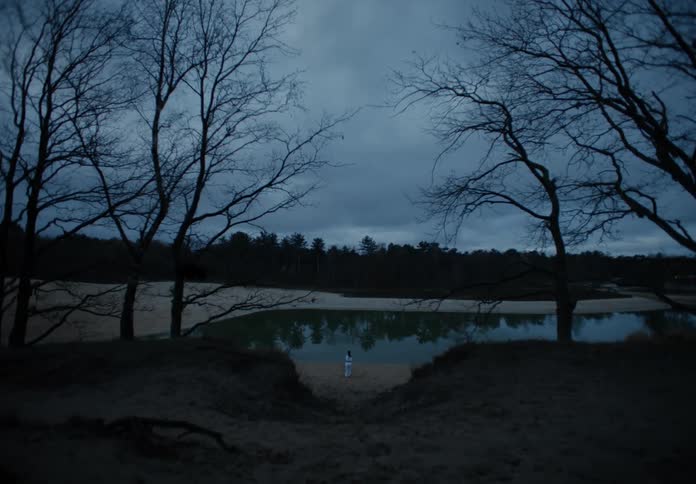 A woman practices martial arts in front of a river during blue hour