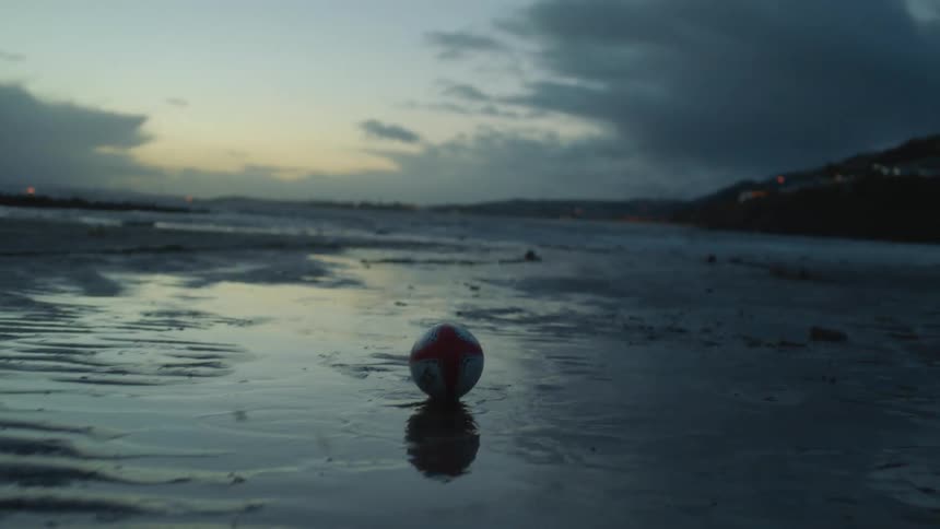 A football is thrown toward the ocean on a beach