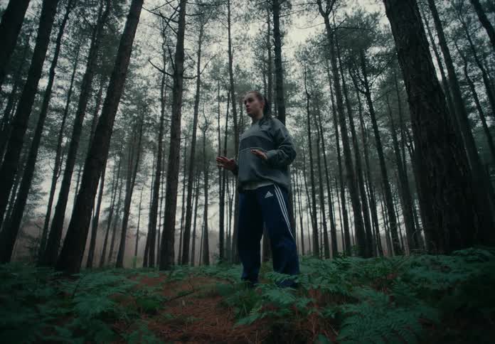 A woman meditates and breathes deeply surrounded by trees in a forest
