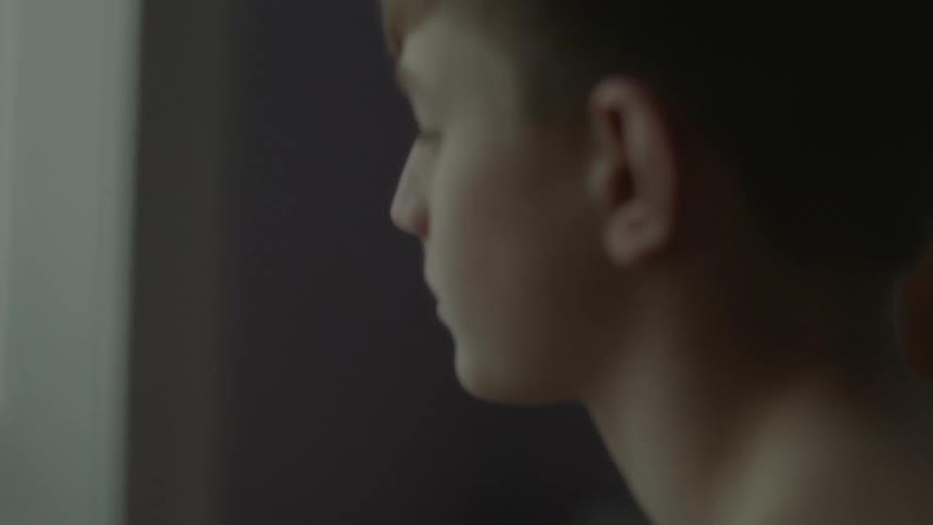Topless boy looks into space in room