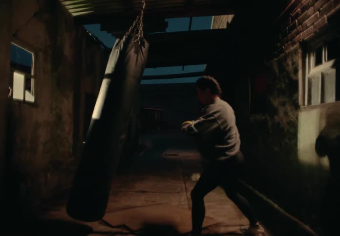 A female is practicing boxing by herself outdoors at night