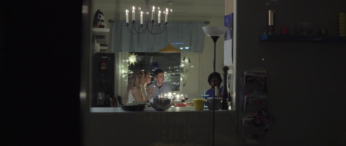 A group of friends sitting around a dinner table in an apartment at night