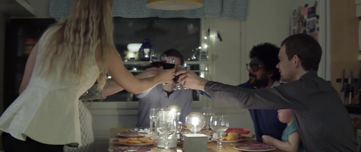 Group of people cheers wine glasses together around a dinner table