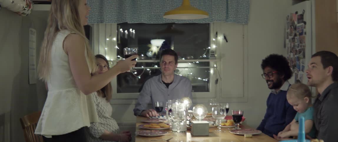Woman Raising a Toast to People at Dinner With Warm Smiles and Celebration