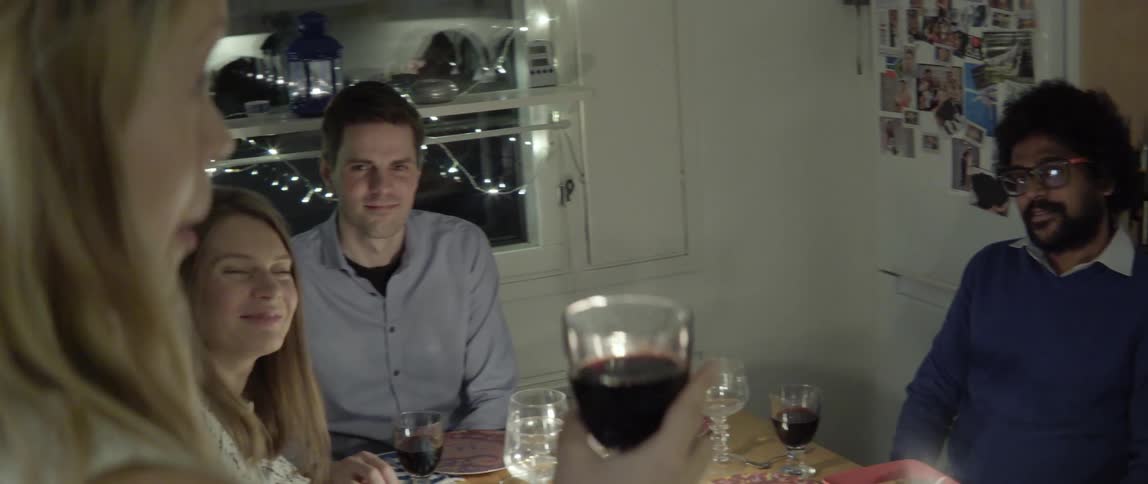 A woman is giving a toast to others at a dining room table