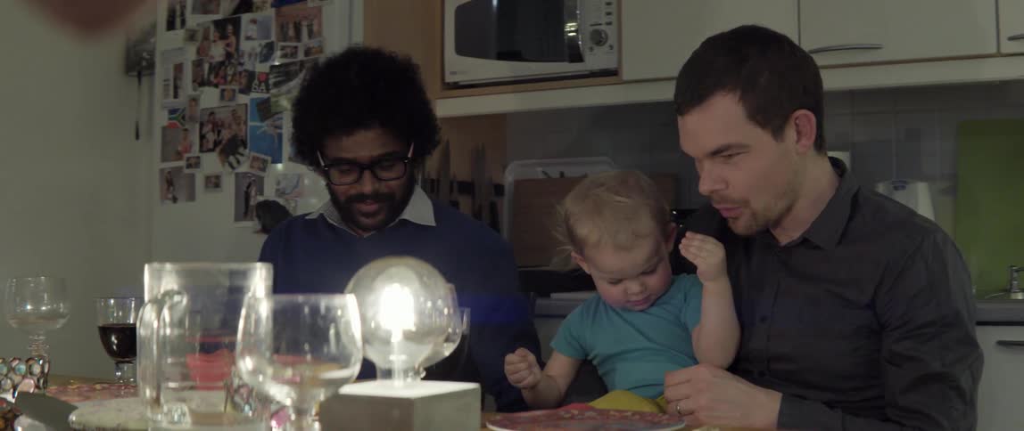 A baby sits in a man's lap at the kitchen table