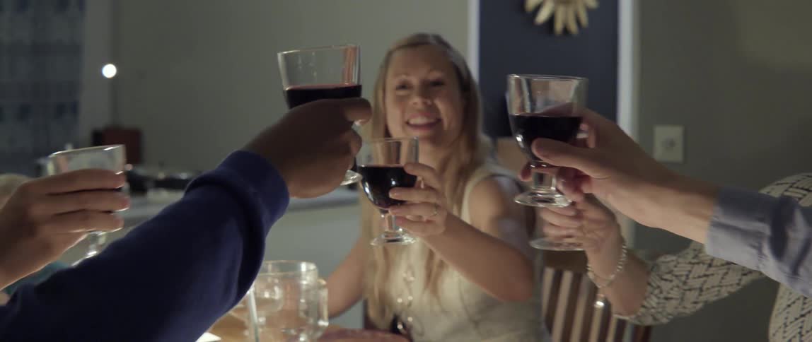 People smile and make a toast at a table together