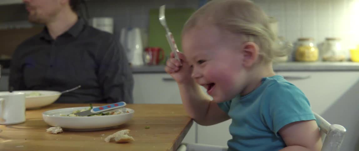 Child laughing joyfully while feeding his mother with loving family moment