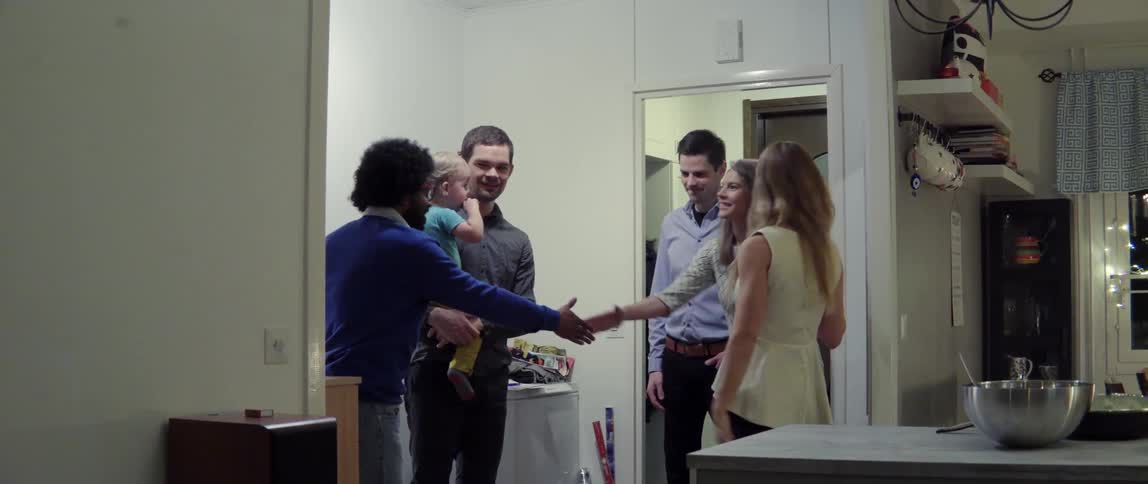 Group of people greeting each other inside a home with warm social energy